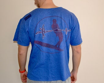 May include: A blue t-shirt with a graphic of a person wakeboarding in a circle on the back. The graphic is in purple and white. The t-shirt has a small blue tag on the left shoulder that says "ONZOW".