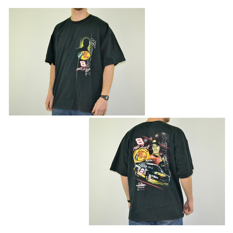 Op de afbeelding: Zwart t-shirt met een afbeelding van een raceauto en coureur met nummer 8. De voorkant toont het Bass Pro Shops-logo en nummer 8. De achterkant heeft een grotere afbeelding van de coureur en auto.