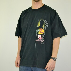 Op de afbeelding: Zwart T-shirt met korte mouwen met een grafisch ontwerp met de tekst "TRUE AIR" en "Bass Pro Shops". Het ontwerp bevat een silhouet en het nummer 8. Het shirt is gemaakt van zacht materiaal.