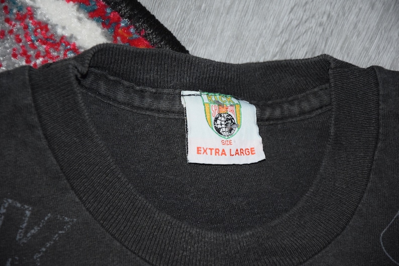 K&ouml;nnte beinhalten: Schwarzes T-Shirt mit einem grafischen Aufdruck. Das Etikett lautet "Kick Start" und "Extra Large".