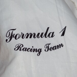 May include: White fabric with black text that reads "Formula 1 Racing Team".