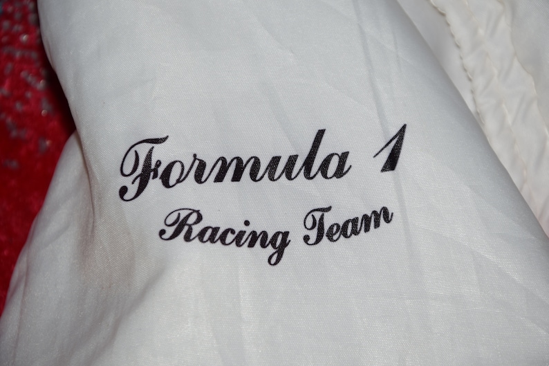 May include: White fabric with black text that reads "Formula 1 Racing Team".