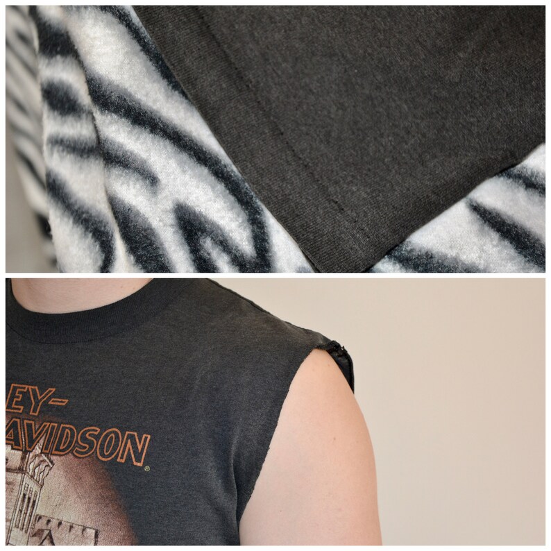 May include: Close-up of a dark gray Harley-Davidson graphic t-shirt with the sleeves cut off. The shirt has an orange graphic and text. The top of the image shows a white and black zebra-striped fabric.