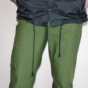 Pu&ograve; includere: Pantaloni cargo verdi con lacci neri.