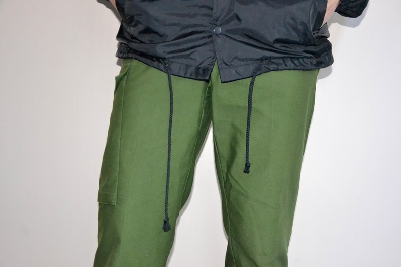 Pu&ograve; includere: Pantaloni cargo verdi con lacci neri.