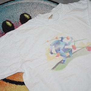 May include: White t-shirt featuring a colourful graphic of a person holding a string of connected circles. The text "intel" is printed on the right sleeve.