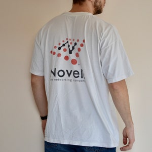 May include: White t-shirt with a black and red logo that says "Novell, the networking company".