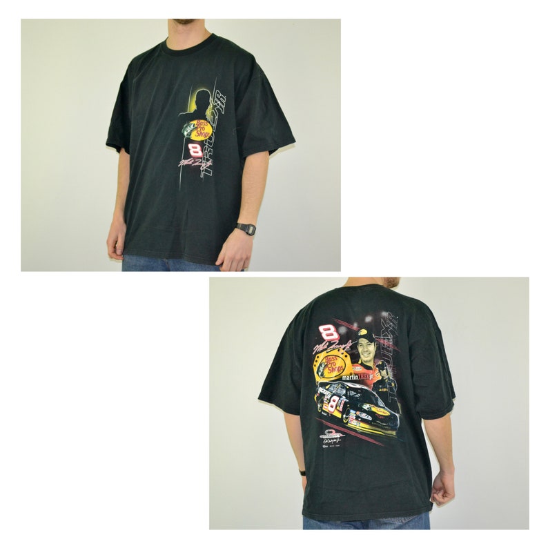 Op de afbeelding: Zwart t-shirt met een afbeelding van een raceauto en coureur met nummer 8. De voorkant toont het Bass Pro Shops-logo en nummer 8. De achterkant heeft een grotere afbeelding van de coureur en auto.