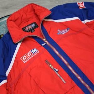 Puede incluir: Chaqueta CCM roja y azul con cierre de cremallera completo. La chaqueta presenta detalles en blanco, el logo de Inter Sport en la manga y el texto "CCM When you're here to play". Tiene un logo de los Canadiens de Montreal.