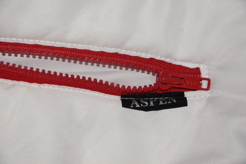 May include: A red zipper with a black label that says "ASPEN" on a white background.