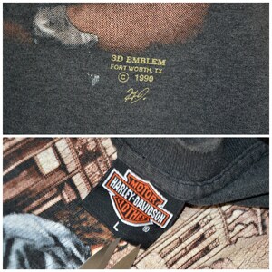 May include: Close-up of a dark gray Harley-Davidson t-shirt tag with the Harley-Davidson logo in orange and white. The tag reads "MOTOR HARLEY-DAVIDSON CLOTHES" and size "L". The shirt also has a 3D EMBLEM tag.