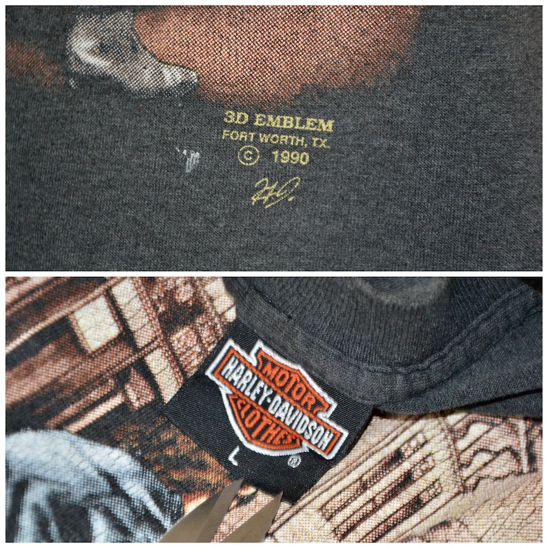 May include: Close-up of a dark gray Harley-Davidson t-shirt tag with the Harley-Davidson logo in orange and white. The tag reads "MOTOR HARLEY-DAVIDSON CLOTHES" and size "L". The shirt also has a 3D EMBLEM tag.