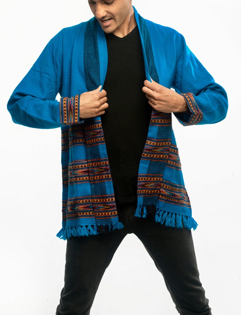 Male model wearing a turquoise cardigan with brown accents and fringe on the ends.