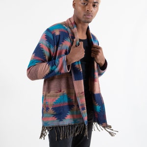 Male model wearing stylish cardigan with fringes on the end. Cardigan is brown with turquoise and blue accents.