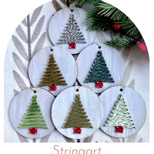 May include: Six circular wooden ornaments featuring string art Christmas trees in various shades of green and white. Each tree is constructed with metallic pins and yarn, topped with a small red square gem at the base. Each ornament has a hole at the top.