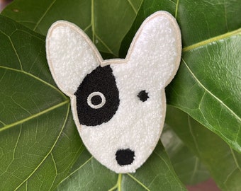 Op de afbeelding: Witte en zwarte geborduurde patch van een hondenkop. De hond heeft een zwarte vlek boven een oog en een zwarte neus.