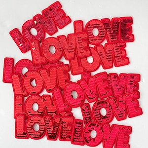 May include: A pile of red sequined patches that spell out the word "LOVE" in all caps.
