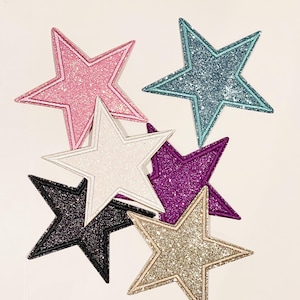 May include: Six sparkly star-shaped patches in various colors, including pink, white, blue, purple, black, and gold.