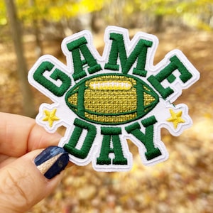 May include: Green and white embroidered patch with a football and the text "GAME DAY".