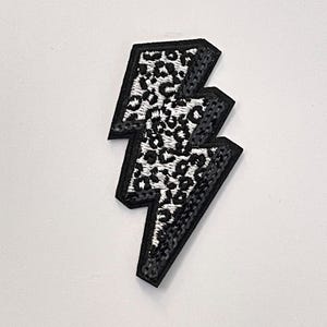 May include: Black and white leopard print lightning bolt iron-on patch.