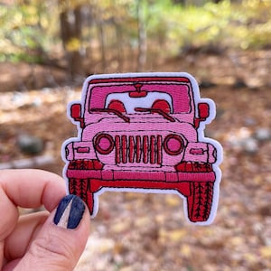 May include: Pink embroidered iron-on patch of a Jeep. The Jeep is facing forward and has a white windshield and red headlights.