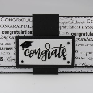 Pu&ograve; includere: Biglietto di laurea bianco e nero con un cappello di laurea nero e la parola "congrats" in lettere glitter nere.