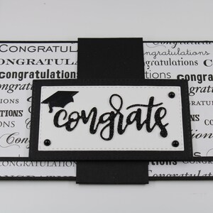 Pu&ograve; includere: Biglietto di laurea bianco e nero con un cappello di laurea nero e la parola "congrats" in lettere glitter nere.