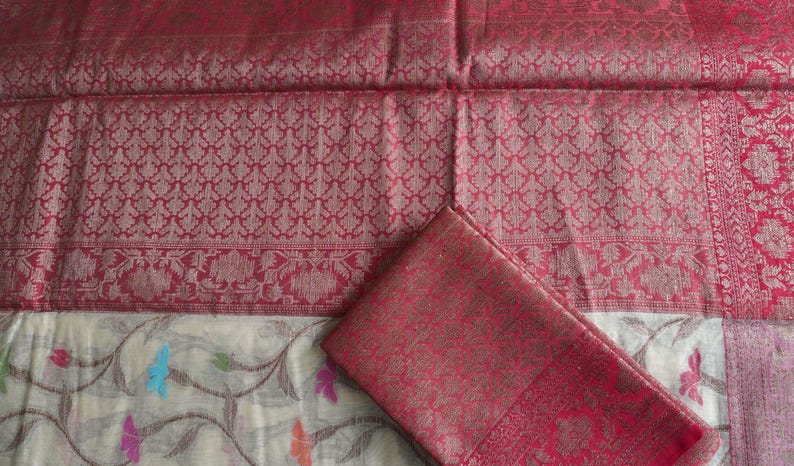 May include: A red and gold patterned textile with a matching folded piece. The fabric features intricate floral and geometric designs. The bottom portion of the textile has a white background with colorful floral and leaf patterns.