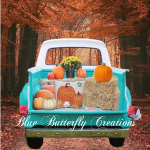 Peut inclure: Un camion vintage bleu turquoise avec une benne remplie de citrouilles et de balles de foin. Un coussin avec le texte "Happy Fall" est dans la benne du camion. Le camion est garé dans une forêt avec des feuilles d'automne.
