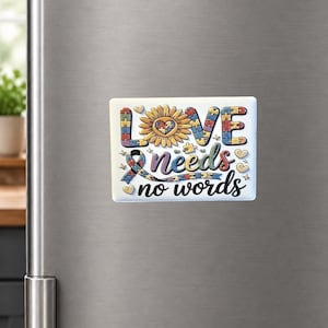 May include: A rectangular magnet with the words "Love needs no words" in a decorative font. The design includes a sunflower, puzzle pieces, and a ribbon, all in vibrant colors. Small heart shapes are scattered around the text.