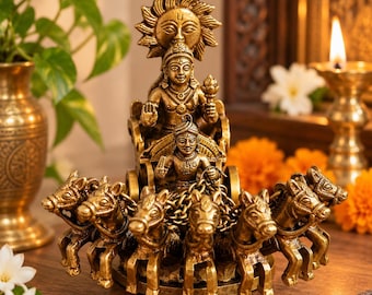 May include: A brass-colored metal sculpture depicting a chariot pulled by seven horses. The chariot carries two figures, with a large sun emblem positioned behind the upper figure. The sculpture features intricate detailing and a metallic finish.
