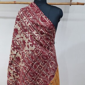 May include: A maroon, beige, and orange kantha quilt with a floral pattern. The quilt is draped over a mannequin.
