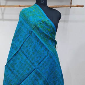 May include: A blue and green kantha shawl with a floral pattern. The shawl is draped over a mannequin.