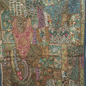 May include: A teal and green textile wall hanging with intricate embroidery and embellishments. The design features a patchwork of patterns, including floral and geometric motifs, with sequins and beads adding texture. The border is a solid teal fabric.