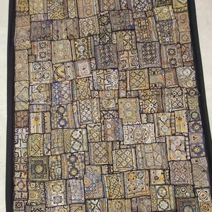 May include: A tapestry wall hanging with a patchwork design. The tapestry is made of various fabrics in shades of brown, beige, and blue. The fabric is decorated with intricate patterns and designs.