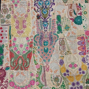 Puede incluir: Un tapiz de pared de patchwork colorido con bordados intrincados y lentejuelas. La tela es una mezcla de blanco, crema, rosa, verde, azul y morado. El diseño presenta motivos florales, patrones de cachemira y formas geométricas.