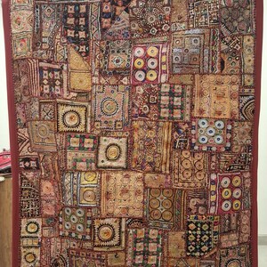 May include: A large, rectangular patchwork textile with a deep red border. The central design is a mosaic of various fabric squares in shades of red, gold, and brown, with intricate embroidered patterns and geometric shapes.