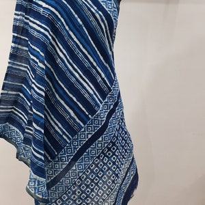 Peut inclure: Une écharpe en coton bleu et blanc à motifs géométriques. L'écharpe est drapé sur un mannequin.