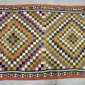 May include: A colorful patchwork rug with a geometric pattern of squares and diamonds. The rug is made of different fabrics in shades of red, orange, yellow, green, blue, and white.