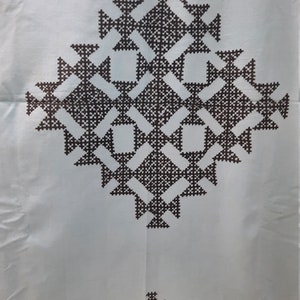 May include: White fabric with a brown geometric pattern. The pattern is made up of repeating squares and triangles.