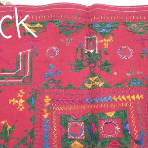 Pu&ograve; includere: Tessuto rosso con ricami intricati in verde, giallo, blu e bianco. La parola "Back" &egrave; scritta in bianco. Il design presenta forme geometriche e motivi floreali, mostrando una lavorazione artigianale dettagliata.