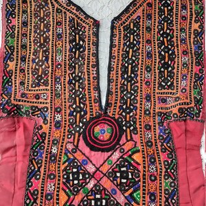 May include: A red embroidered fabric panel with intricate geometric patterns and colorful beads. The panel features a central circular design with a black background and colorful accents.