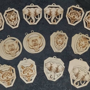 May include: A collection of laser-cut wooden ornaments featuring various animal portraits. The designs include tigers, elephants, wolves, and bears, each with intricate details. The ornaments have a natural wood finish and a small hole for hanging.