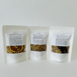 May include: Three white pouches with labels for facial steam. The pouches contain dried herbs and flowers. The labels read "Refresh Facial Steam with Sweet Orange Essential Oil", "Detox Facial Steam with Peppermint Essential Oil", and "Calm Facial Steam with Lavender Essential Oil".