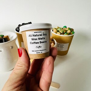 May include: A small brown paper cup filled with soy wax melts that smell like coffee. The label reads "All Natural Soy Wax Melts Coffee Beans Coffee" and "Hand-poured in Breawood, CA Net Wt 1 oz".