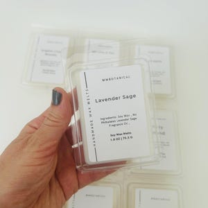 May include: A clear plastic clamshell container holding white wax melts labeled MWBOTANICAL Lavender Sage. The label lists ingredients as soy wax, no phthalates, and lavender sage fragrance oil, with a net weight of 1.8 ounces or 75.5 grams.