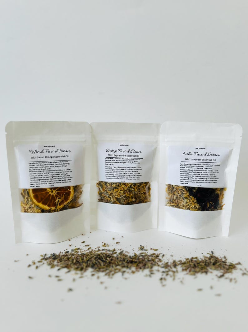 May include: Three white pouches with labels that read "Refresh Facial Steam with Sweet Orange Essential Oil", "Detox Facial Steam with Peppermint Essential Oil", and "Calm Facial Steam with Lavender Essential Oil". Each pouch contains dried herbs and flowers.