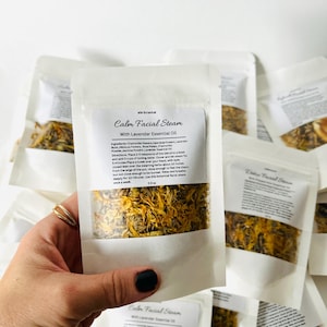 May include: A white paper pouch with a clear window showing dried yellow and orange flower petals. The pouch is labeled "Calm Facial Steam with Lavender Essential Oil" and includes instructions for use. WW Botanical is printed on the pouch.
