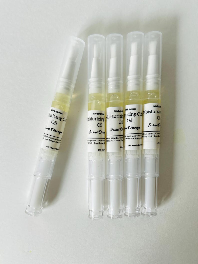 May include: Five clear, pen-shaped containers of moisturizing cuticle oil. The containers have white caps and bases, with a clear section in the middle showing the yellow oil. The label reads "Moisturizing Cuticle Oil Sweet Orange".