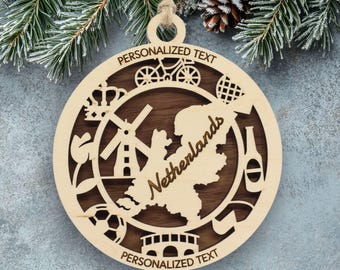 Pode incluir: Um ornamento circular de madeira com um mapa dos Países Baixos cortado a laser no centro e a palavra Netherlands escrita. A borda inclui ícones de uma bicicleta, coroa, moinho de vento, tulipa, bola de futebol, ponte e uma garrafa.